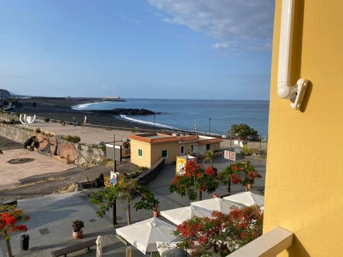 a view of a beach with white umbrellas and the ocean at Tazacorte Beach and also Luz y Mar apartments in Puerto