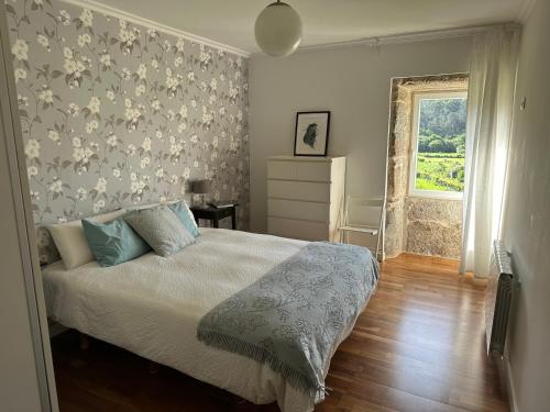 um quarto com uma cama com uma parede estampada floral em Casa La Antigua Escuela em Mondariz
