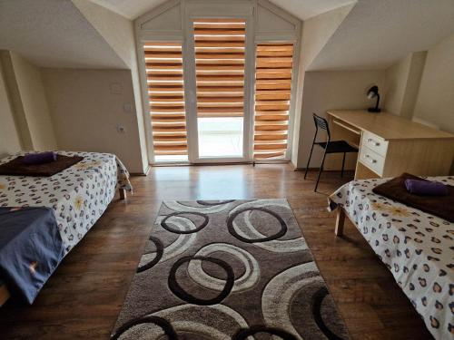a bedroom with two beds and a desk and a rug at Town Square House in Gevgelija