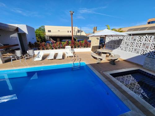 una piscina con sedie, tavolo e ombrellone di Hotel Pousada Paraiso Avaré ad Avaré