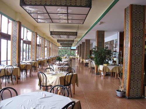 a dining hall with tables and chairs and windows at Hotel Capo Noli in Noli
