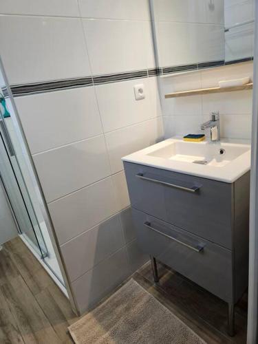 une salle de bain blanche avec un lavabo et une douche dans l'établissement Chez Louise, Appartement T3 à deux pas du centre, à Luchon