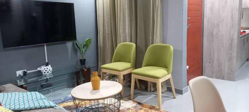 a living room with two green chairs and a tv at Zachi Apartments in Kitwe