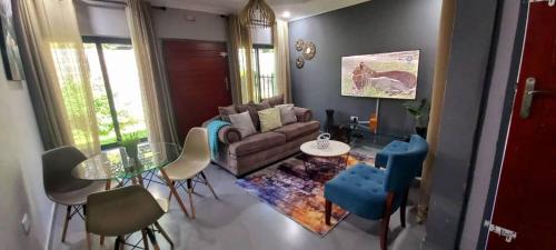 uma sala de estar com um sofá, uma mesa e cadeiras em Zachi Apartments em Kitwe