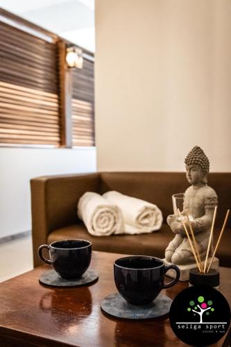 a table with two cups and a statue of a child at Seliga Sport Apartments & SPA in Lesznowola