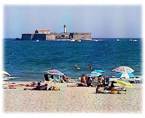 a group of people on a beach with a lighthouse at Lovicéa Balnéo Suite, 200m plage in Le Grau-dʼAgde