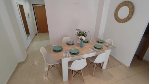 a dining room table with white chairs and a wooden table at Apartamento planta baja con piscina in Denia
