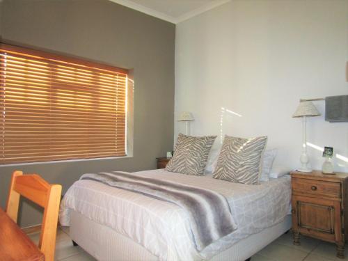 a bedroom with a bed with a window and a wooden table at De Wawielhuis in Calitzdorp