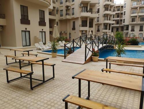 a group of tables and benches next to a pool at Úplně nový apartmán v Tropical resort in Hurghada