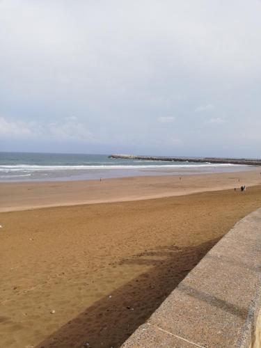 a beach with people walking on the sand and the ocean at Mehdia Ville in Plage de Mehdia