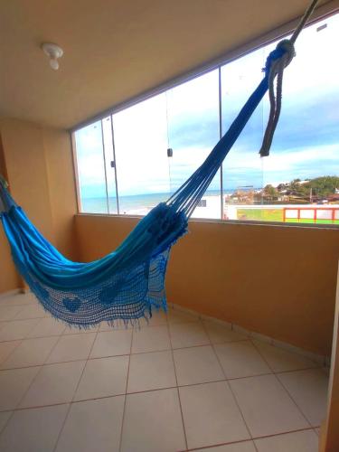 a blue hammock in a room with a view of the ocean at Amazônia Praia Hotel in Tibau