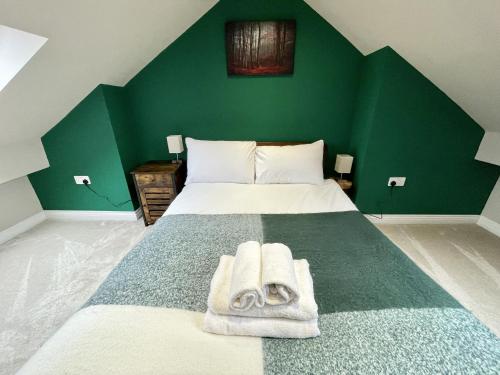 a green bedroom with a bed with towels on it at Modern Maisonette in Vibrant Bristol, Free Parking in Bristol