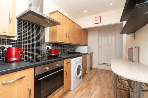 a kitchen with wooden cabinets and a washer and dryer at Spacious 2 bed Southville flat near Harbourside in Bristol