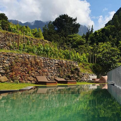 a pool with a person laying on the ground next to a stone wall at Terrabona Nature & Vineyards in Boaventura