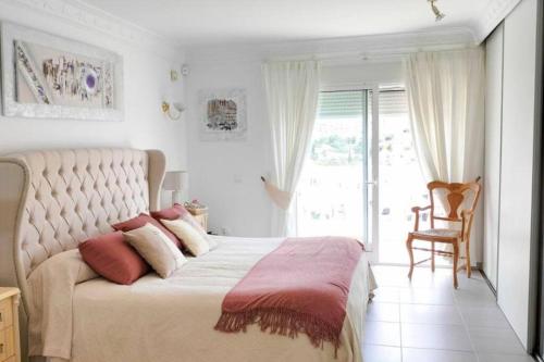 um quarto com uma grande cama branca com almofadas vermelhas em Villa Torre Nueva, Mijas Costa em La Cala de Mijas