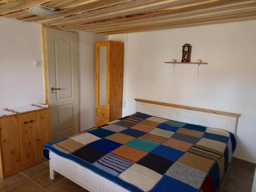 1 dormitorio con 1 cama con una manta colorida en Két Kerék Vendégház, en Patvarc