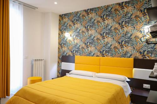 a bedroom with a yellow bed with a floral wallpaper at Palazzo Archeo in Pompei