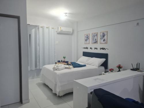 a white bedroom with a bed and a table at Manaíra Flat 206 Em frente ao shopping Manaíra in João Pessoa