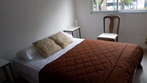 1 dormitorio con 1 cama, 1 silla y 1 ventana en Dto 46 en La Plata