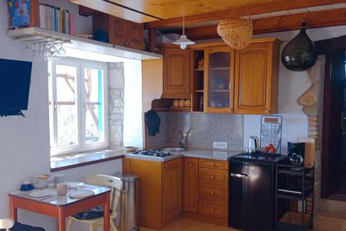 eine Küche mit Holzschränken und einem schwarzen Kühlschrank in der Unterkunft Casa Delle Olive in Mošćenička Draga