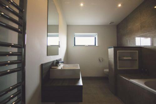 W łazience znajduje się umywalka, toaleta i lustro. w obiekcie Jog Lodge 22 - 3 Bed Sea-View w mieście Wick