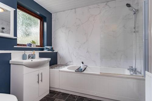 ein Badezimmer mit einer weißen Badewanne und einem Waschbecken in der Unterkunft Templepatrick family home beside the Rabbit hotel in Templepatrick
