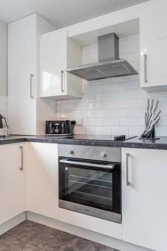 a kitchen with white cabinets and a stove top oven at Templepatrick family home beside the Rabbit hotel in Templepatrick
