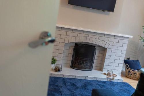 a living room with a brick fireplace with a tv at Templepatrick family home beside the Rabbit hotel in Templepatrick