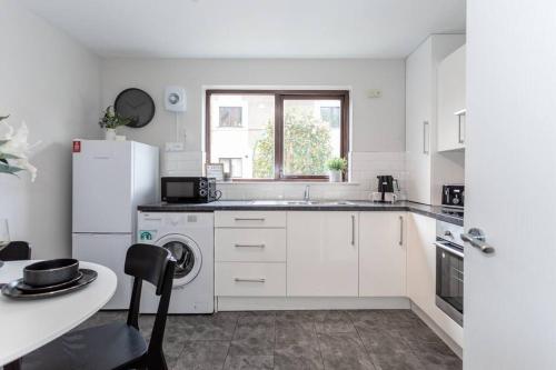a white kitchen with a sink and a refrigerator at Templepatrick family home beside the Rabbit hotel in Templepatrick