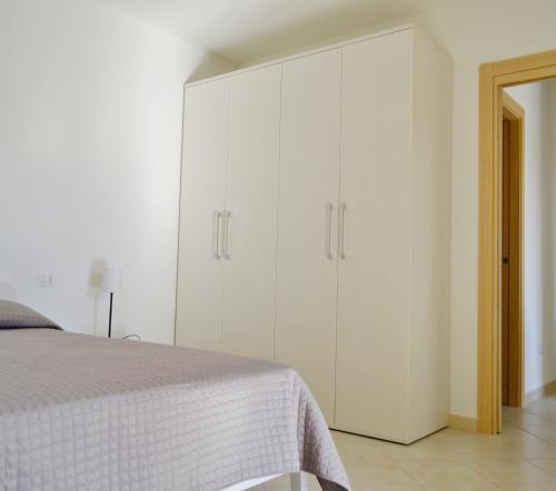 a white bedroom with a bed and white cabinets at GF Apartments La Vigna in Badesi