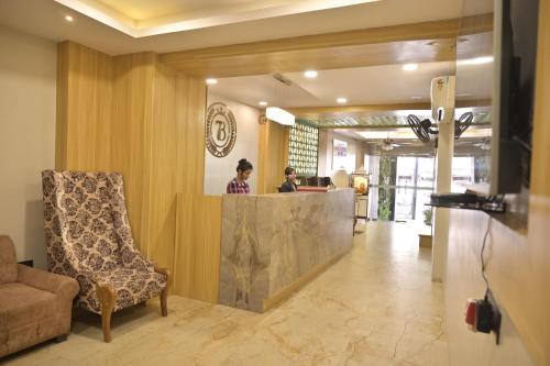 two people standing at a counter in a lobby at Hotel 7-B in Chhatarpur