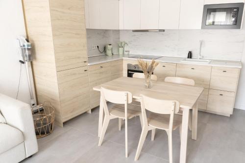 una cucina con tavolo in legno e armadietti bianchi di Apartamento con Parking a 50m de la playa a Sant Antoni de Calonge