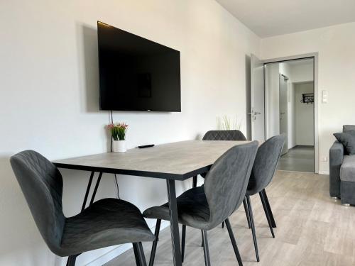 een eettafel met stoelen en een televisie aan de muur bij Trippel M Apartments Stuttgart Zuffenhausen in Stuttgart