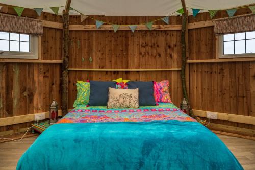 a bedroom with a blue bed in a wooden wall at Hatters Meadows Glamping in Ely