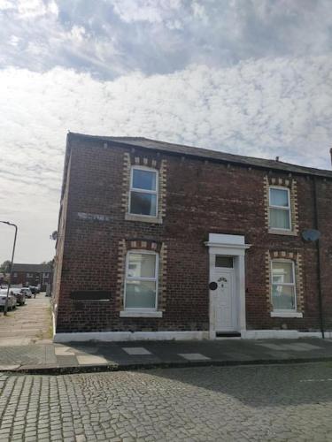 a brick building with a white door on a street at Family Home Near City Centre in Carlisle