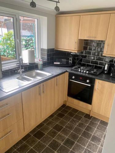 a kitchen with wooden cabinets and a sink and a stove at Family Home Near City Centre in Carlisle