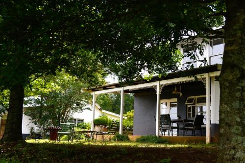 a white house with a porch with a table and chairs at The Knoll Historic Guest Farm in Hilton