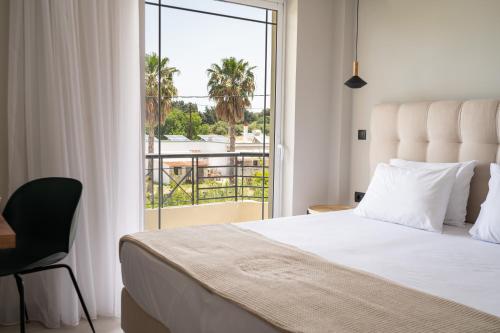 a bedroom with a bed and a balcony with palm trees at Aelia Prime Experience 2 in Kos Town