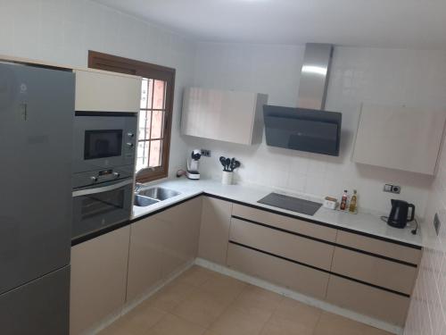 cocina con armarios blancos, fregadero y microondas en House Parra, en San Juan de los Terreros