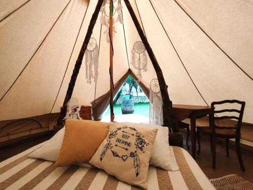 Bett in einem Zelt mit Kissen darauf in der Unterkunft Écuries de Laramière in Laramière