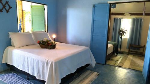 a bedroom with a white bed with a bowl of flowers on it at Casa da Floresta Santo André in Santo André