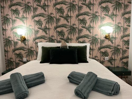 - une chambre avec un grand lit et du papier peint en palmier dans l'établissement LA VERRIÈRE. Les Locations ISAHORA c'est aussi plusieurs appart' de Standing à 2 pas du Château d'Eu, des Falaises du Tréport, de MERS les Bains et aux portes de la BAIE DE SOMME, à Eu