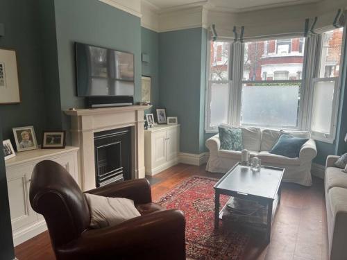 - un salon avec un canapé et une cheminée dans l'établissement Four Bedroom modern Victorian Wandsworth House, à Londres