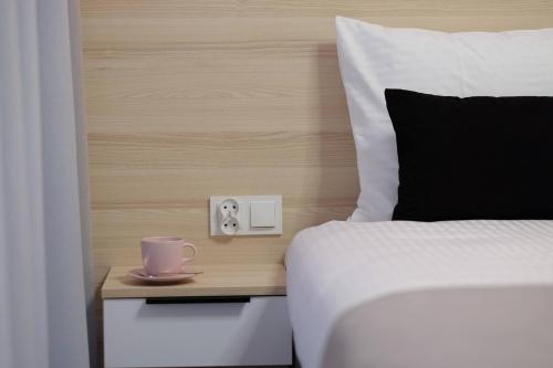 a bed with a cup on a night stand next to a bed at Apartamenty Centrum in Białystok