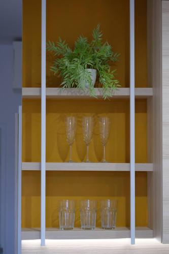 a shelf with wine glasses and a potted plant at Apartamenty Centrum in Białystok