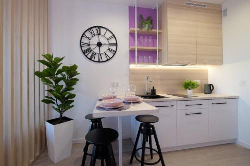 a kitchen with a table and a clock on the wall at Apartamenty Centrum in Białystok