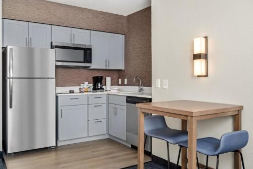 a kitchen with a white refrigerator and a table at Residence Inn by Marriott Chicago Naperville/Warrenville in Warrenville