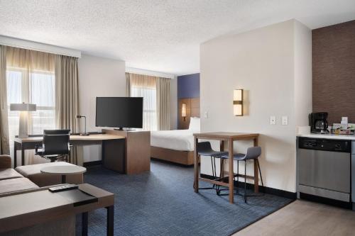 a hotel room with a bed and a table and chairs at Residence Inn by Marriott Chicago Naperville/Warrenville in Warrenville