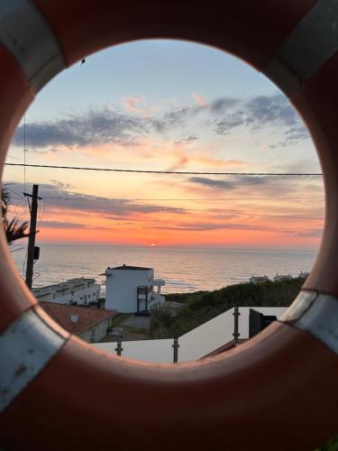 a view of the ocean through a round window at Mãe Home Foz in Foz do Arelho