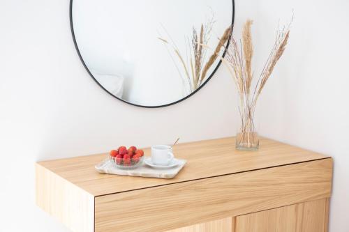 a mirror on top of a wooden dresser with a bowl of fruit at Adria Luxury Apartments in Nydri